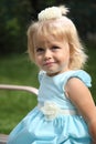 Sweet smiling little girl with long blond hair, sitting on grass in summer park, closeup outdoor portrait. Royalty Free Stock Photo